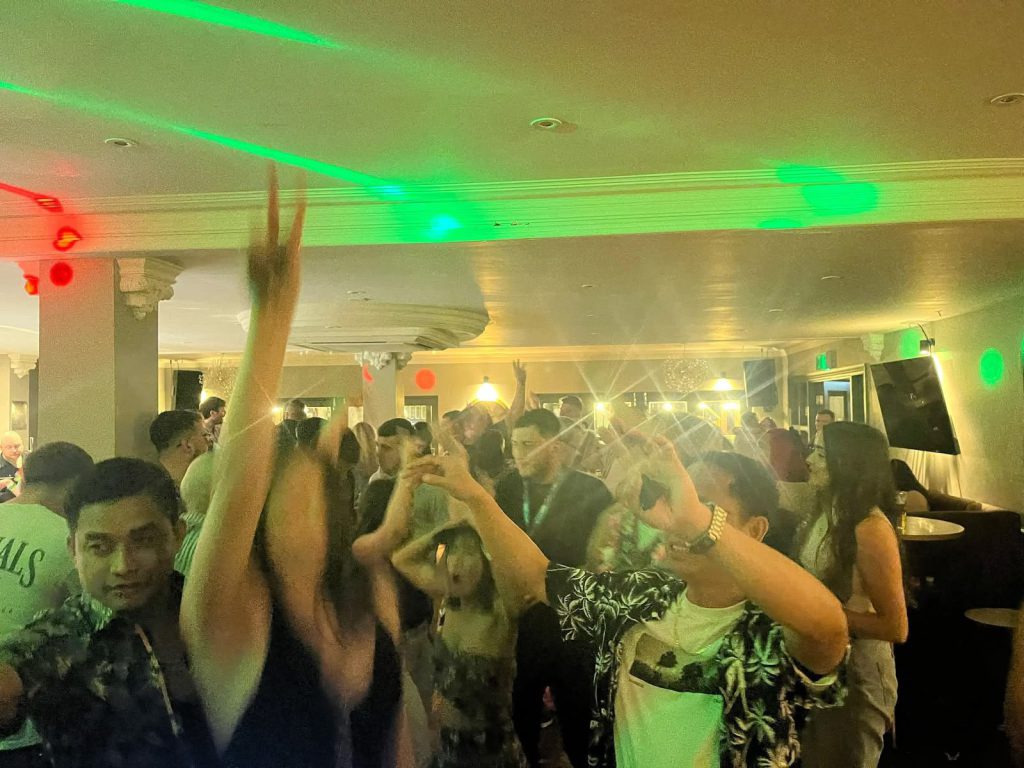 Guests dancing under green and red disco lighting at a party