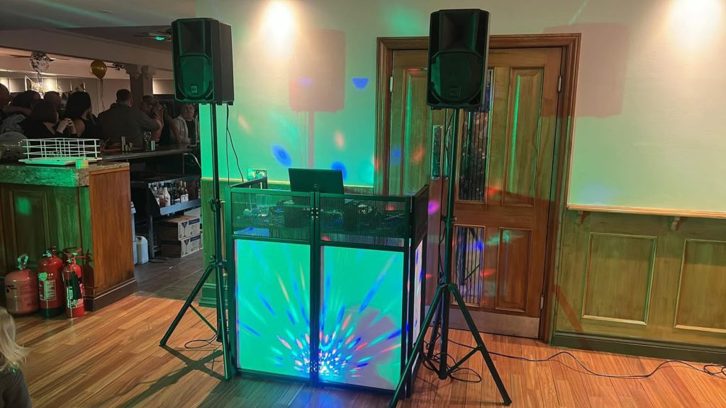 Hatter Entertainment DJ booth with lighting and speakers set up at an event