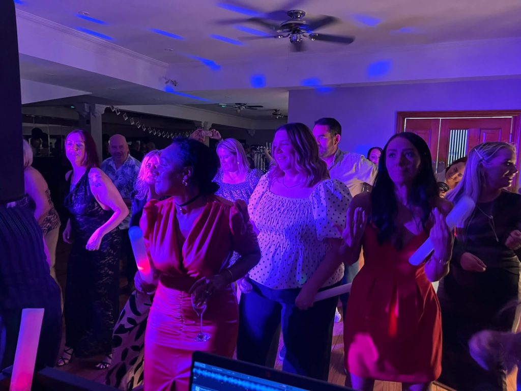 Guests dancing under pink and purple uplighting